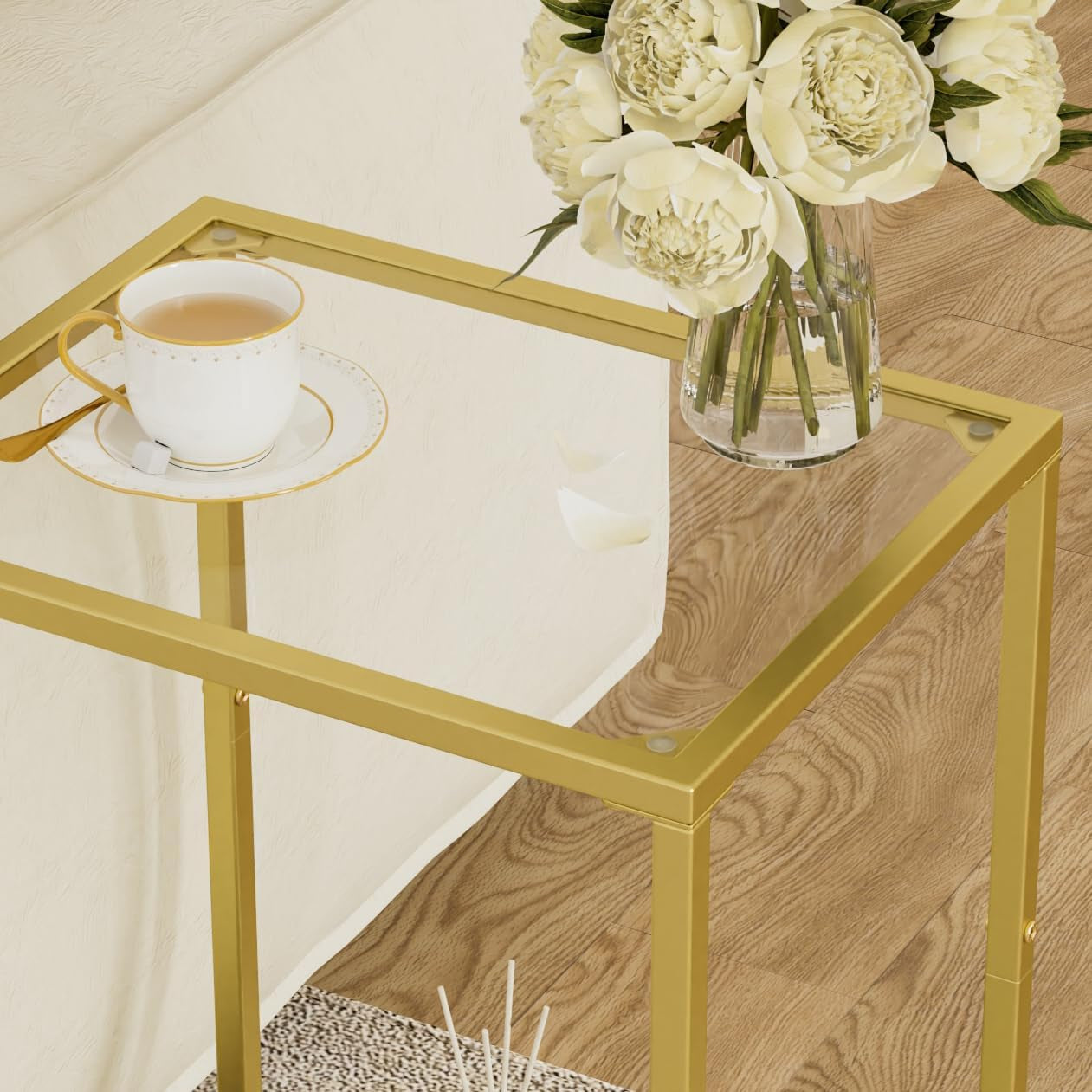 Close-up of a gold metal frame and tempered glass top with a teacup and vase partially visible