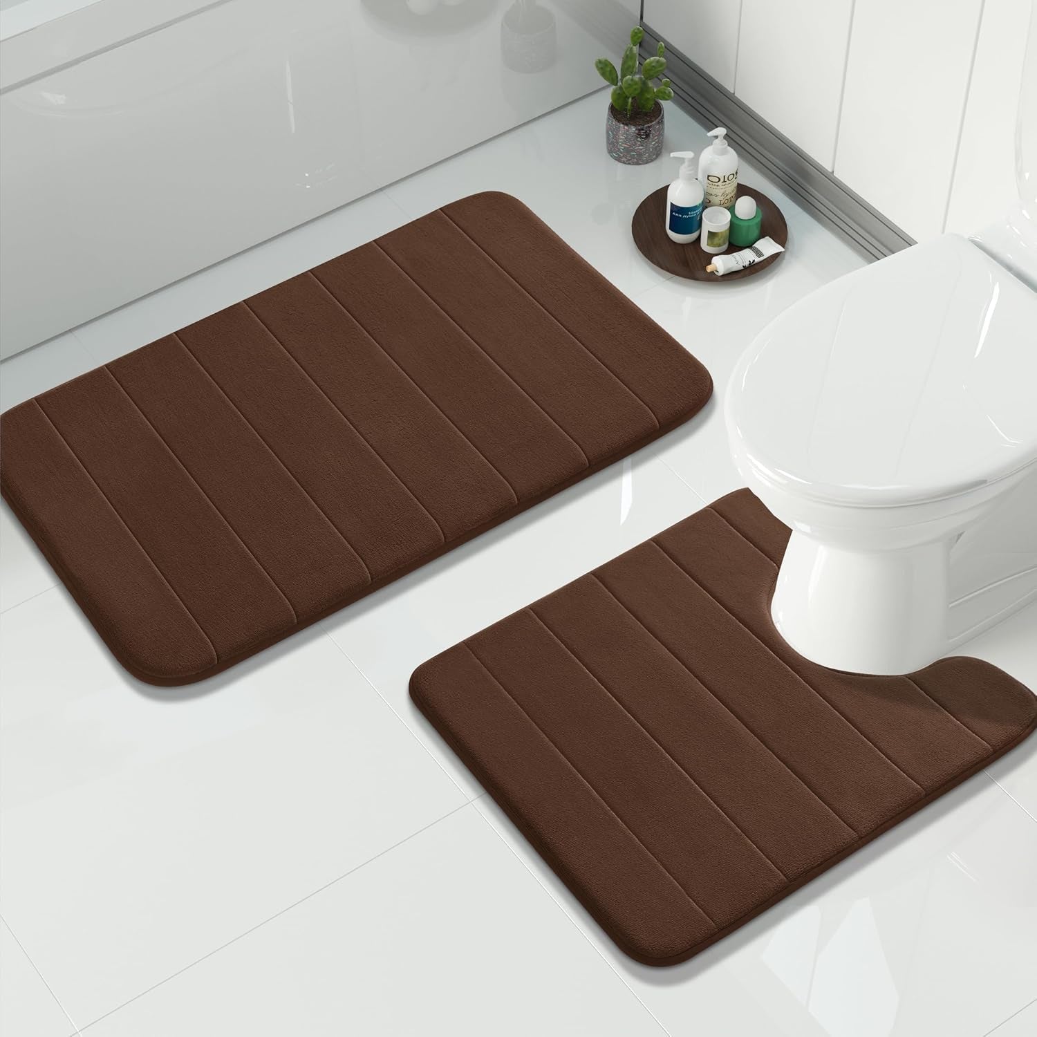 Overhead bathroom view of two rectangular brown memory-foam bath mats by tub and toilet