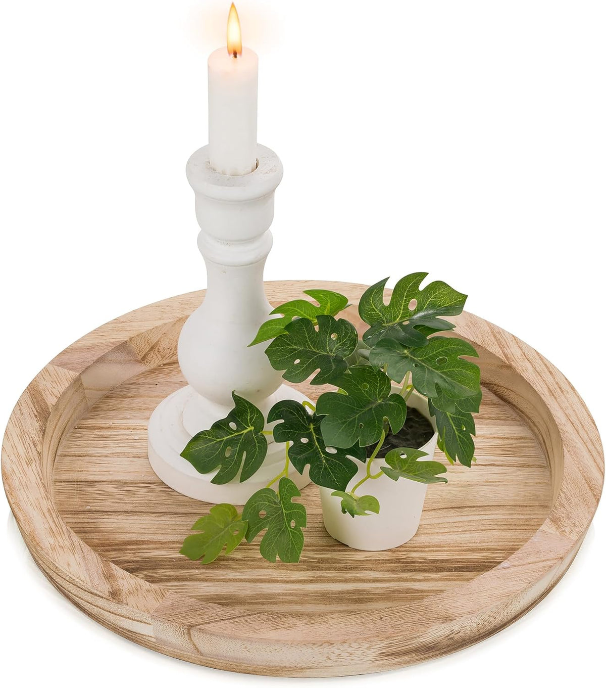 Top view of a light wood round tray holding a white candlestick and a small potted green plant