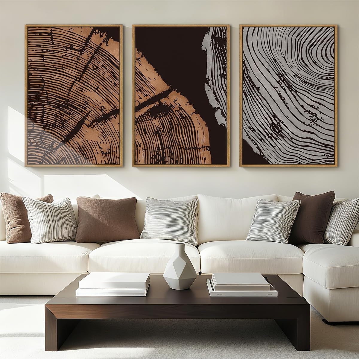 Three framed abstract wood-grain prints in brown and gray tones hung above a cream sectional sofa and dark coffee table.
