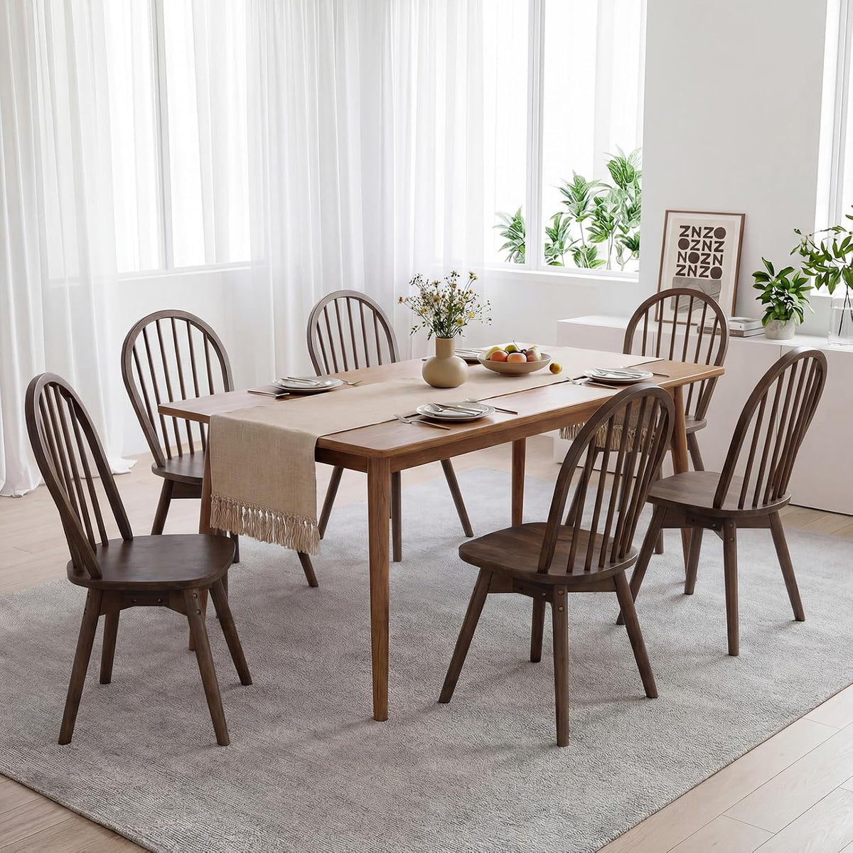 Multiple walnut Windsor chairs placed around a rectangular dining table in a bright, airy room