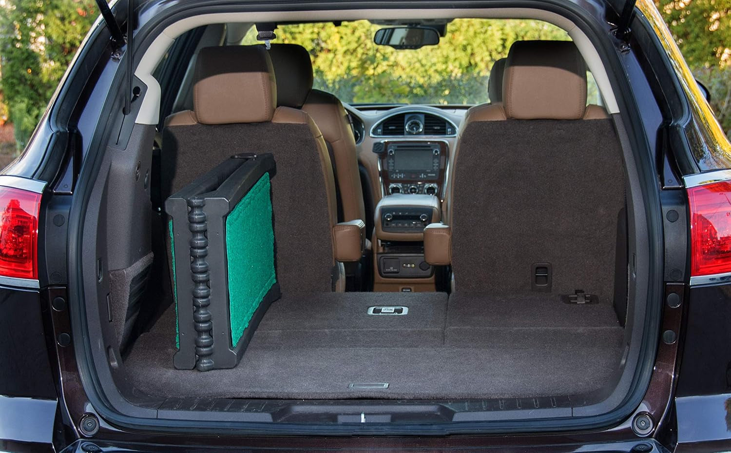 Bi-fold pet ramp folded upright with green traction panels stored inside the open cargo area of an SUV