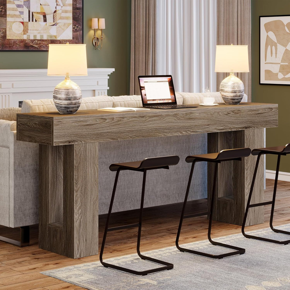Grey console used as a tall counter with three metal stools, laptop and lamps on the tabletop.