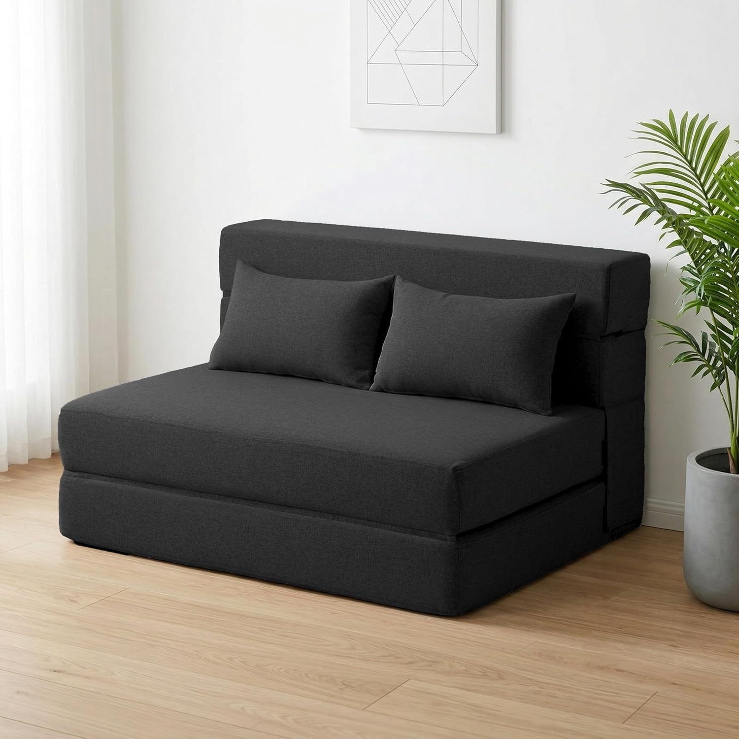 Dark gray folding sofa bed in sofa position with two matching pillows angled front view