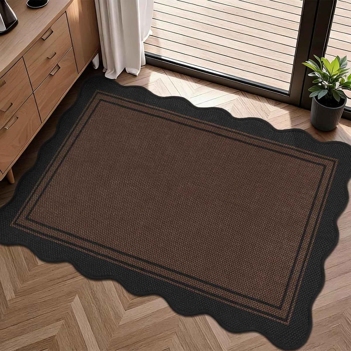 Top-down angle of a brown scalloped rug with dark border on herringbone wood floor