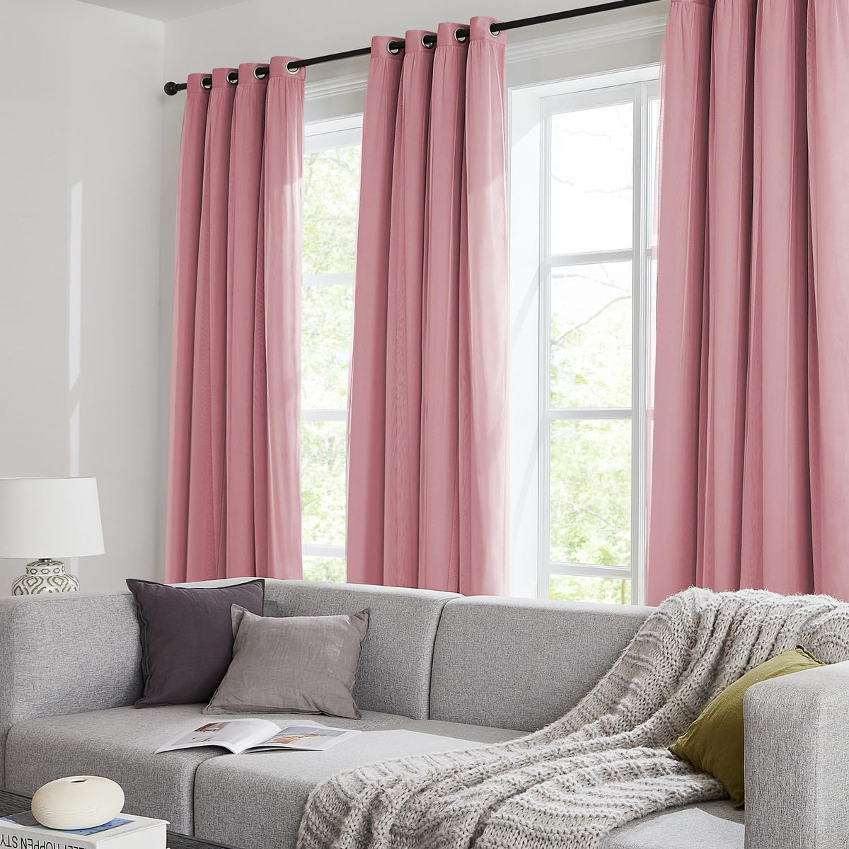 Living room window with floor-length dusty pink grommet curtains and a gray sectional sofa.