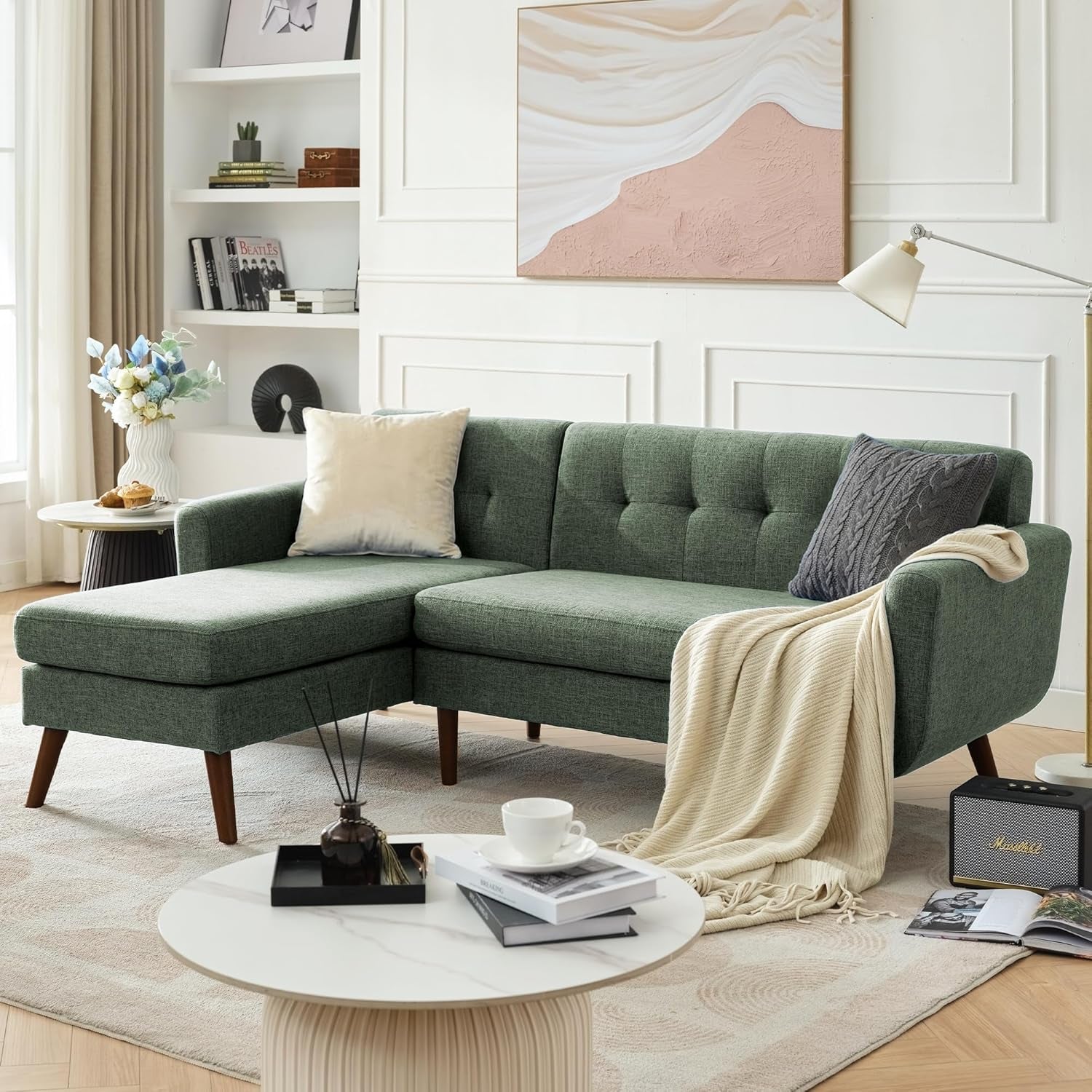 Olive green tufted sectional with chaise, decorative pillows and blanket draped
