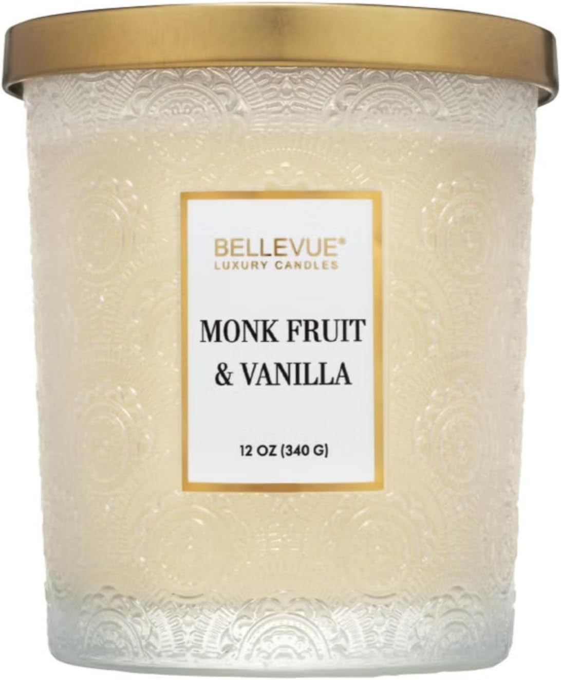 Front close-up of an embossed ivory glass candle jar with a gold lid and centered label.