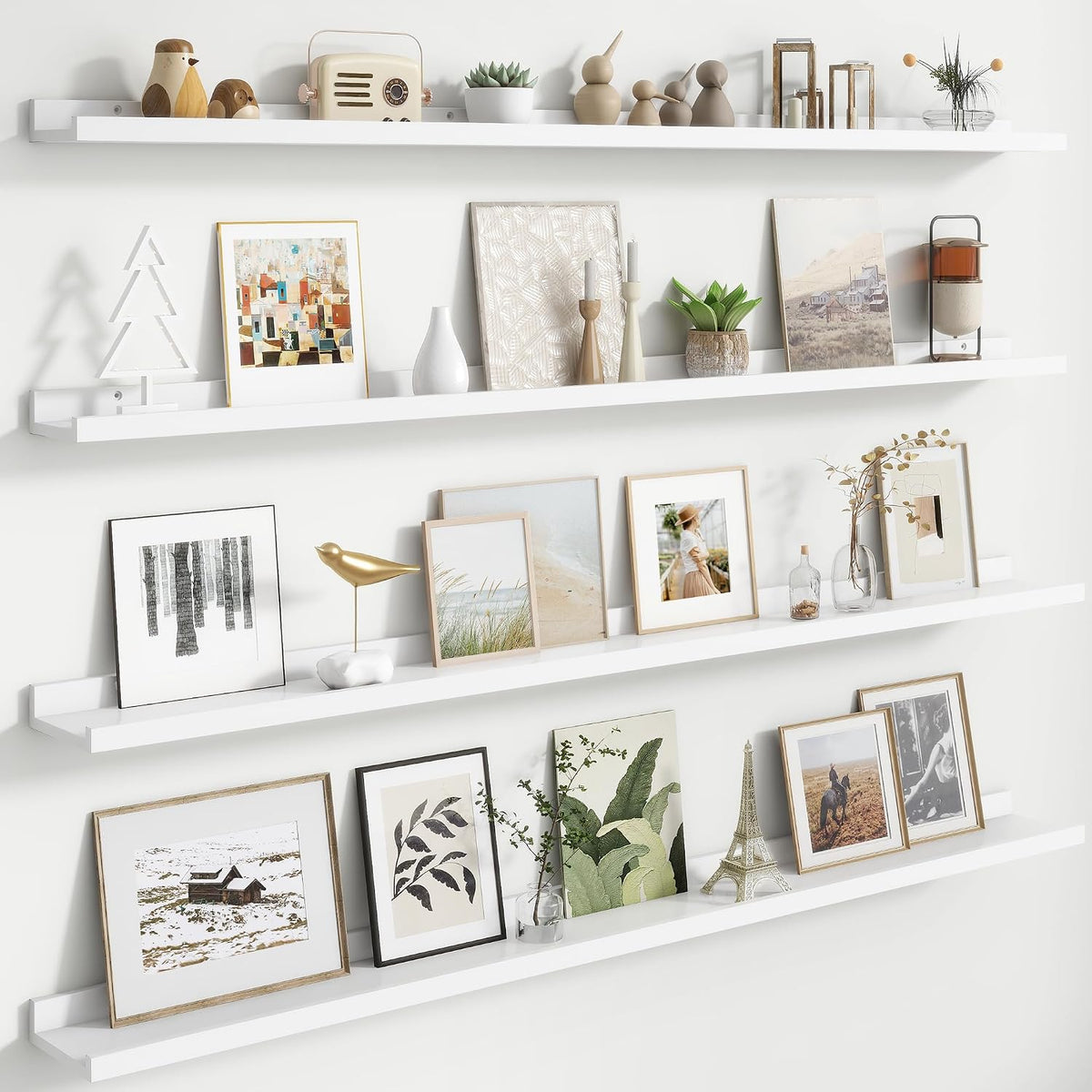 Three white floating picture ledges styled with frames, a gold bird sculpture and small vases