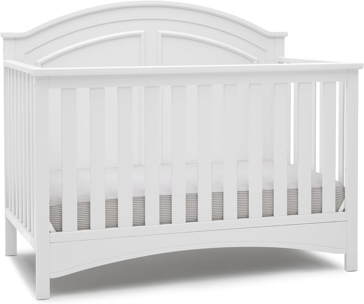Front view of a white convertible crib with arched paneled headboard and vertical slats