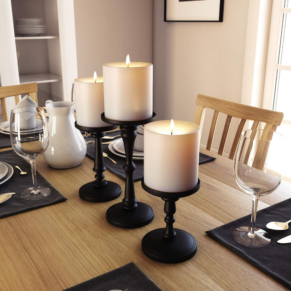 Matte black pillar candle holders arranged as a dining table centerpiece with glassware and dinnerware