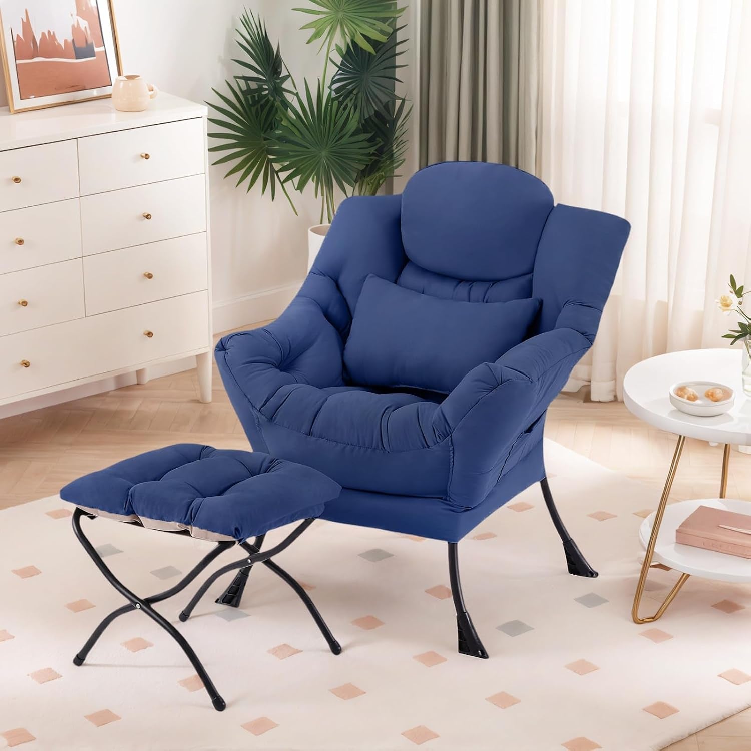 Navy blue upholstered lounge chair with matching ottoman and lumbar pillow in a bright living room.