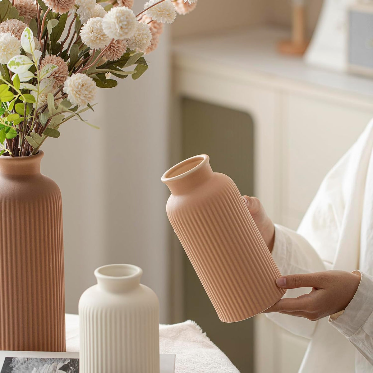 Person holding a medium matte terracotta ribbed vase angled to show the wide opening and vertical texture.
