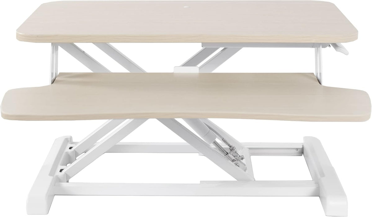 Side view of light-wood top standing desk converter with white frame and keyboard tray