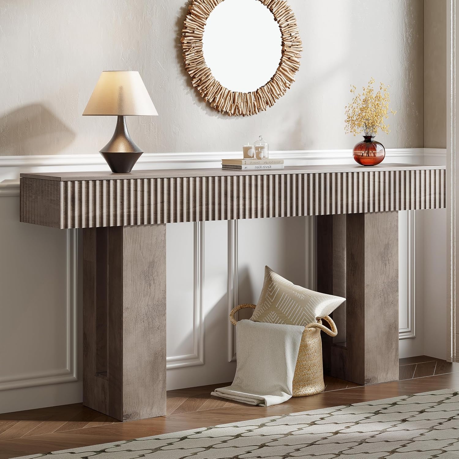 Dark charcoal console in a neutral hall with a round driftwood-style mirror and basket of pillows below.