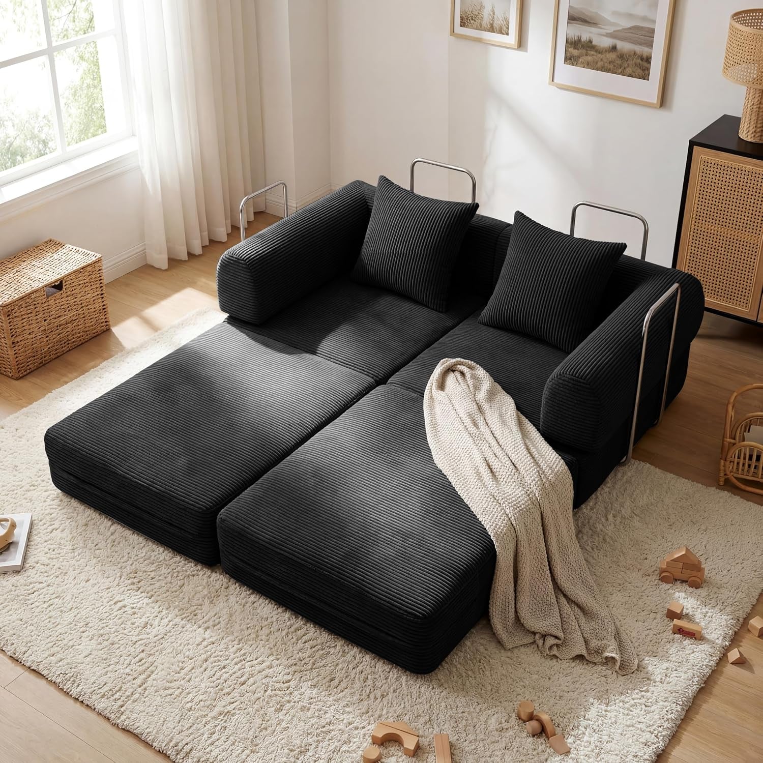 Top-down view of the sofa unfolded into two low black corduroy mattress panels with pillows