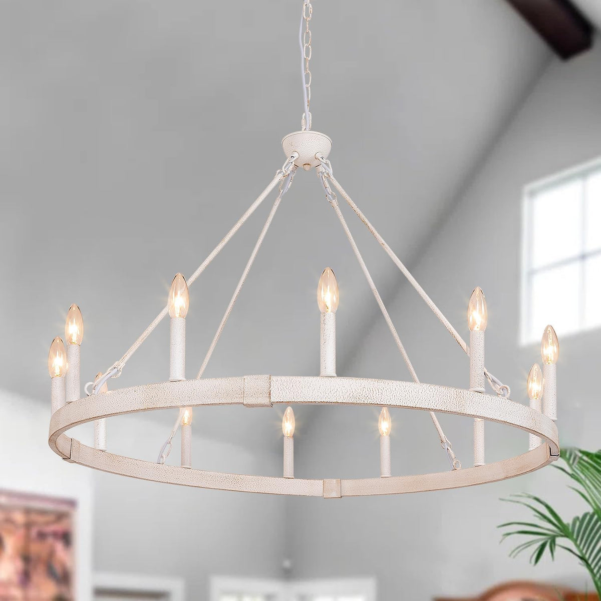 Close-up of a distressed white metal ring chandelier with lit candle bulbs and textured straps to ceiling
