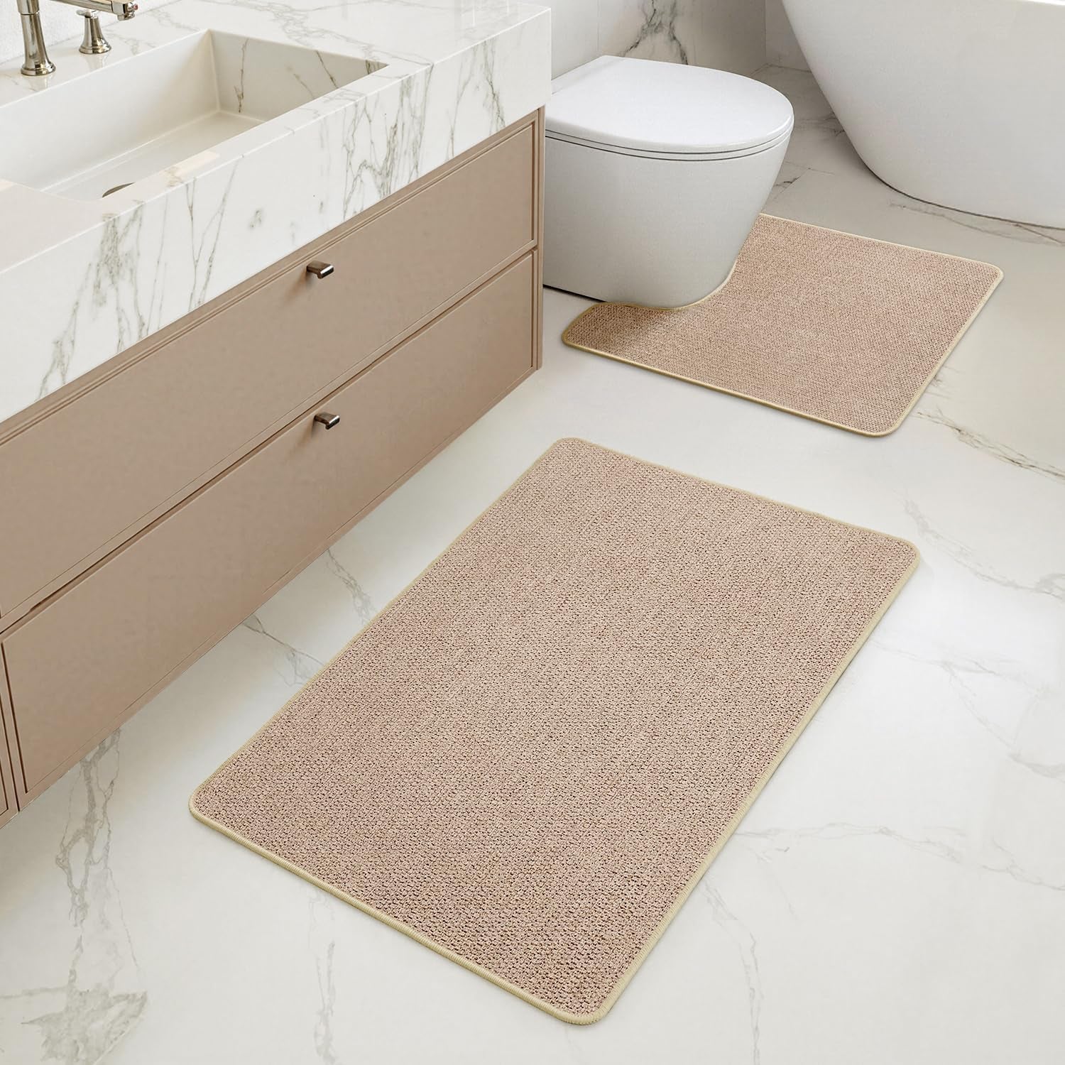 Beige 2-piece bathroom rug set arranged by toilet and vanity in a marble-floored bathroom, angled top view