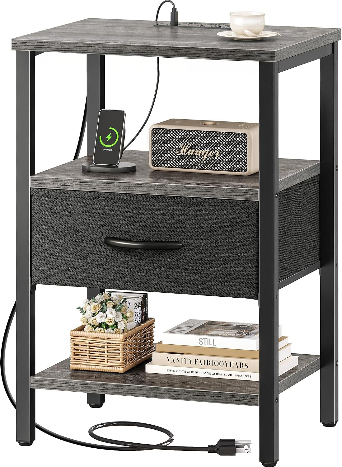 Three-tier nightstand with gray wood surfaces, black metal frame and dark gray fabric drawer, shown with charger and decor.