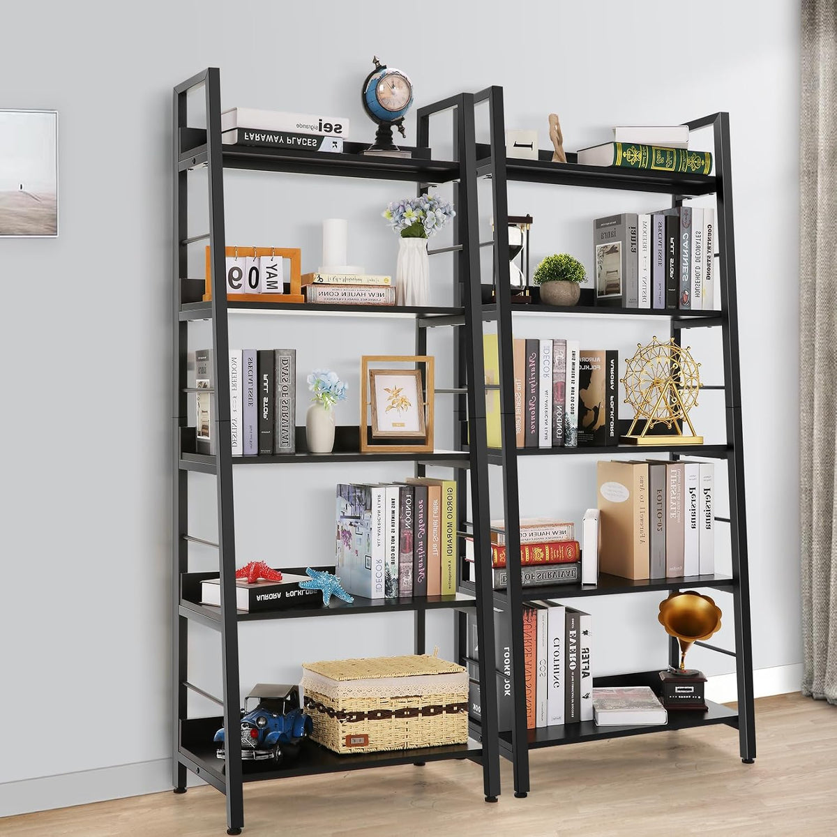 Two black ladder bookcases side-by-side filled with books, plants and decorative accents against a gray wall