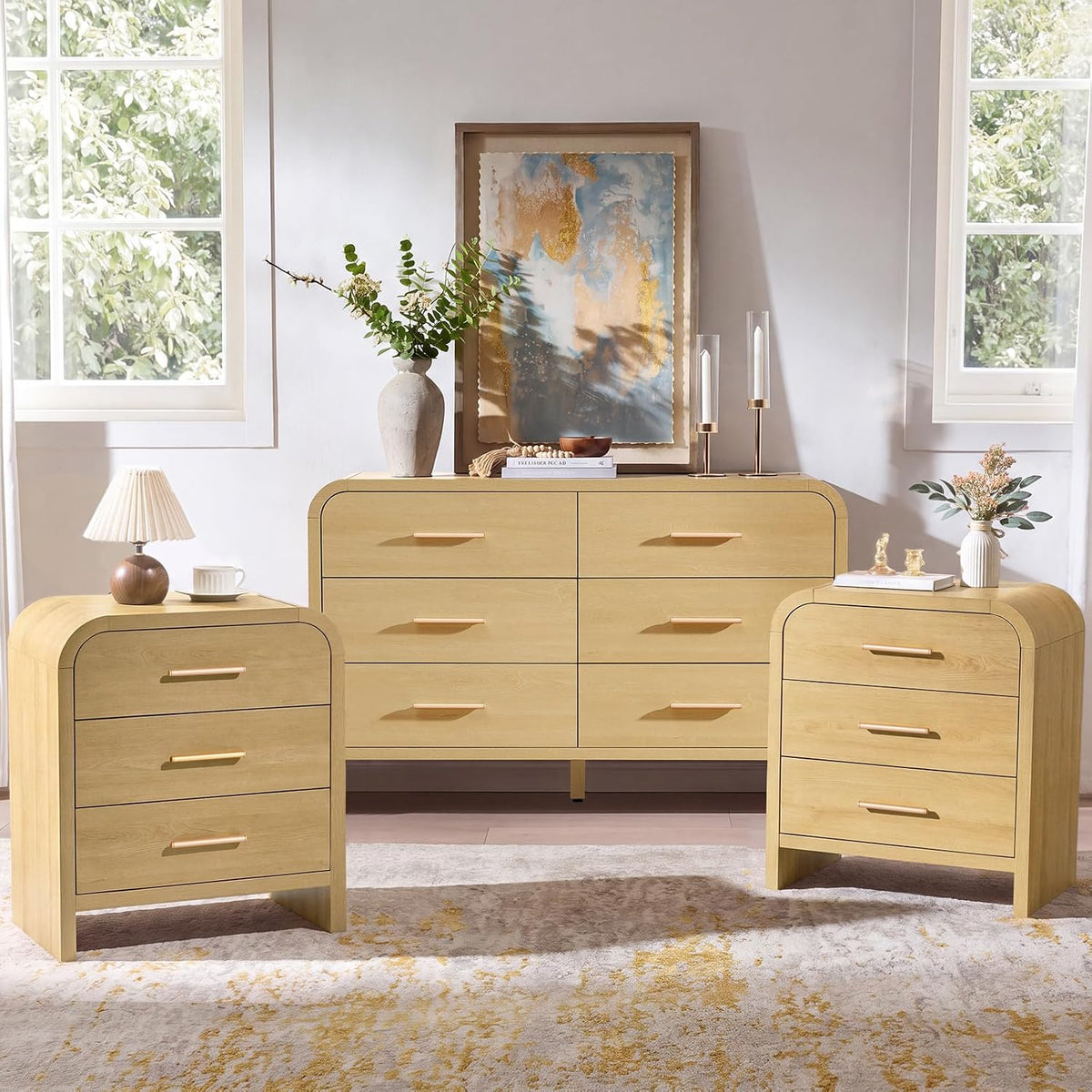Wider frontal view of the three-piece light wood set with framed art, vases and two tall candleholders on the dresser.