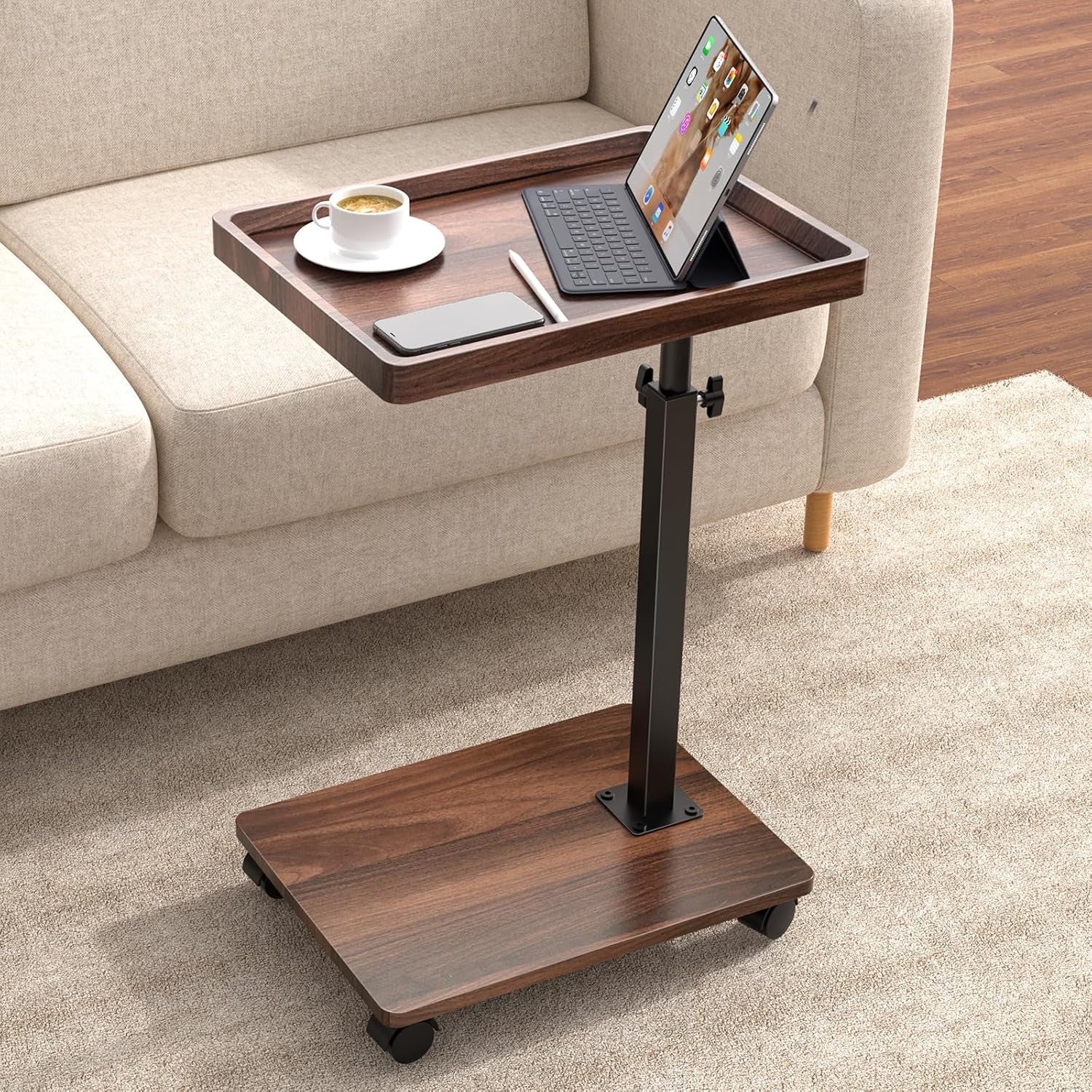 Walnut brown C-shaped side table angled front view next to a beige sofa with tablet and cup on tray