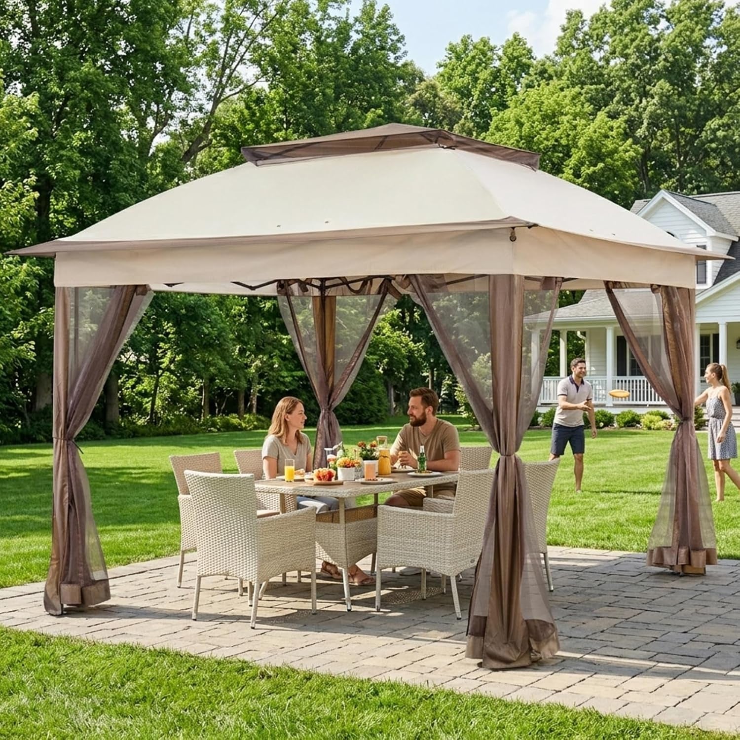 Beige gazebo on patio with people dining at table and tied mesh curtains in a backyard setting