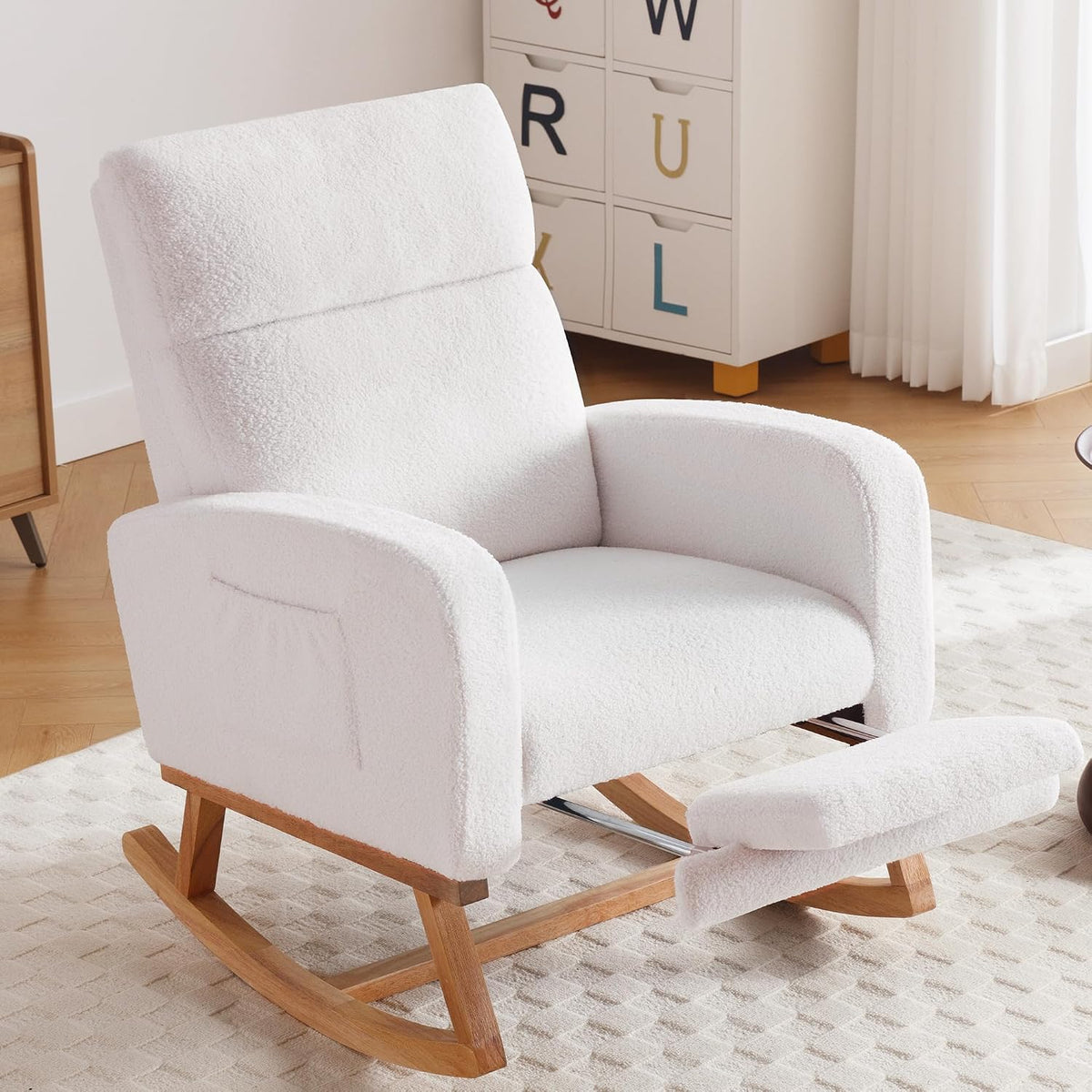 White fabric rocking chair with footrest extended, wooden rocker base in a nursery setting