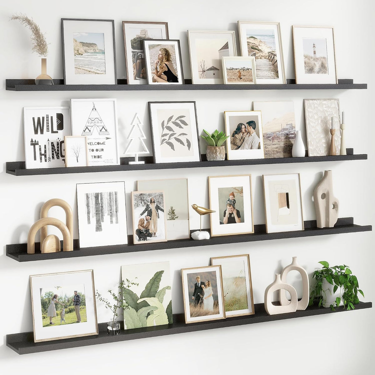 Three black floating ledges across a white wall displaying frames, ceramics and greenery