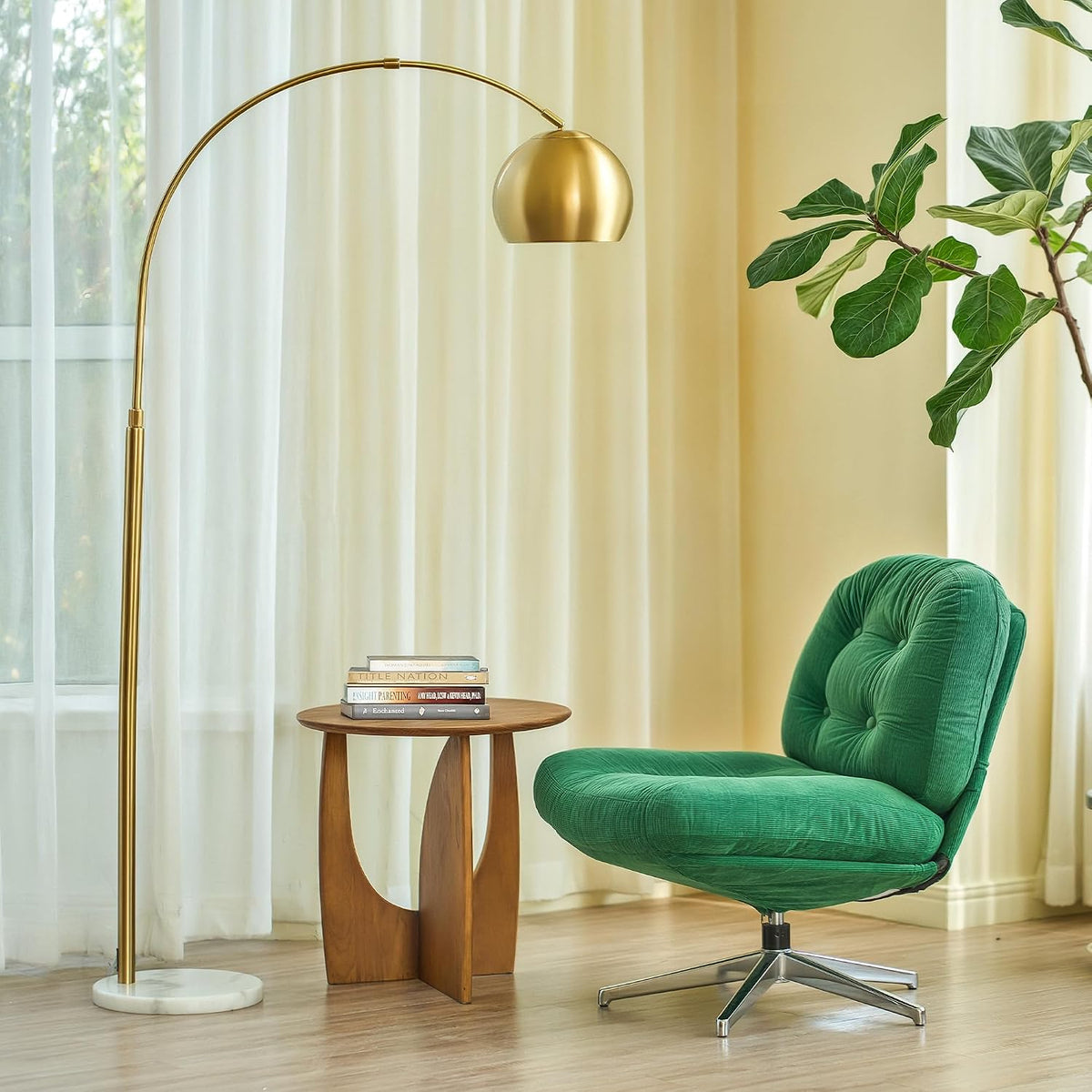 Gold arc floor lamp with round white marble base beside a green lounge chair in a living room setting