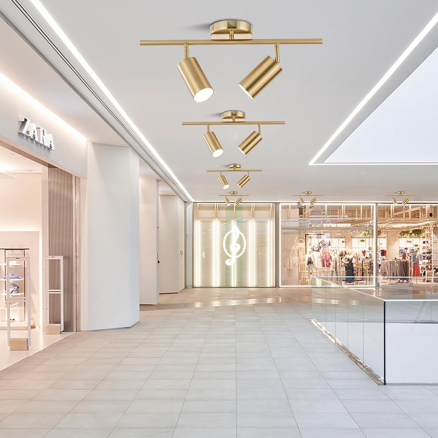 Multiple gold 2-light track fixtures installed in a spacious retail corridor ceiling for ambient directional lighting
