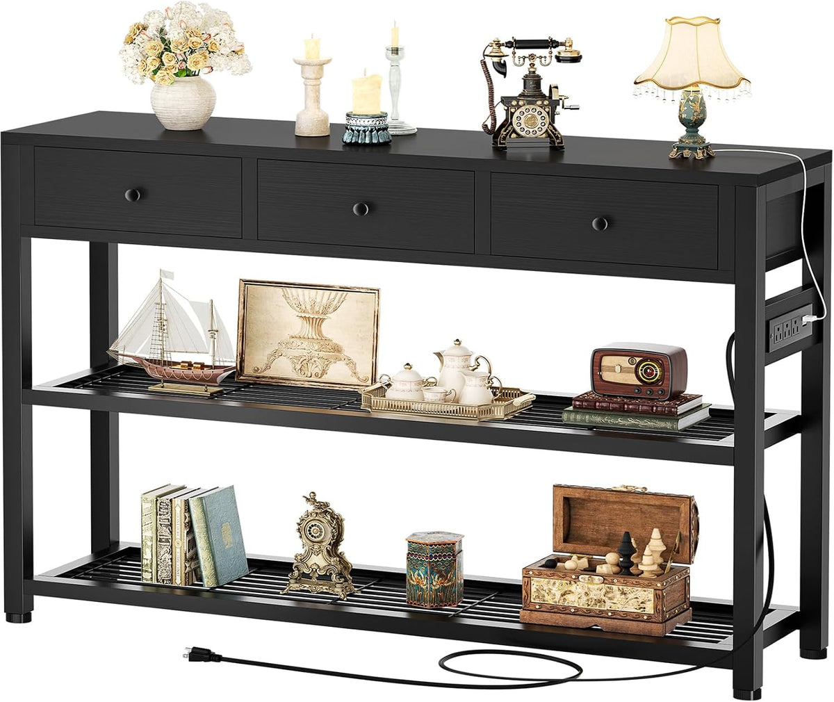 Black console table front view with three drawers, decorative items on top and cord trailing from right side