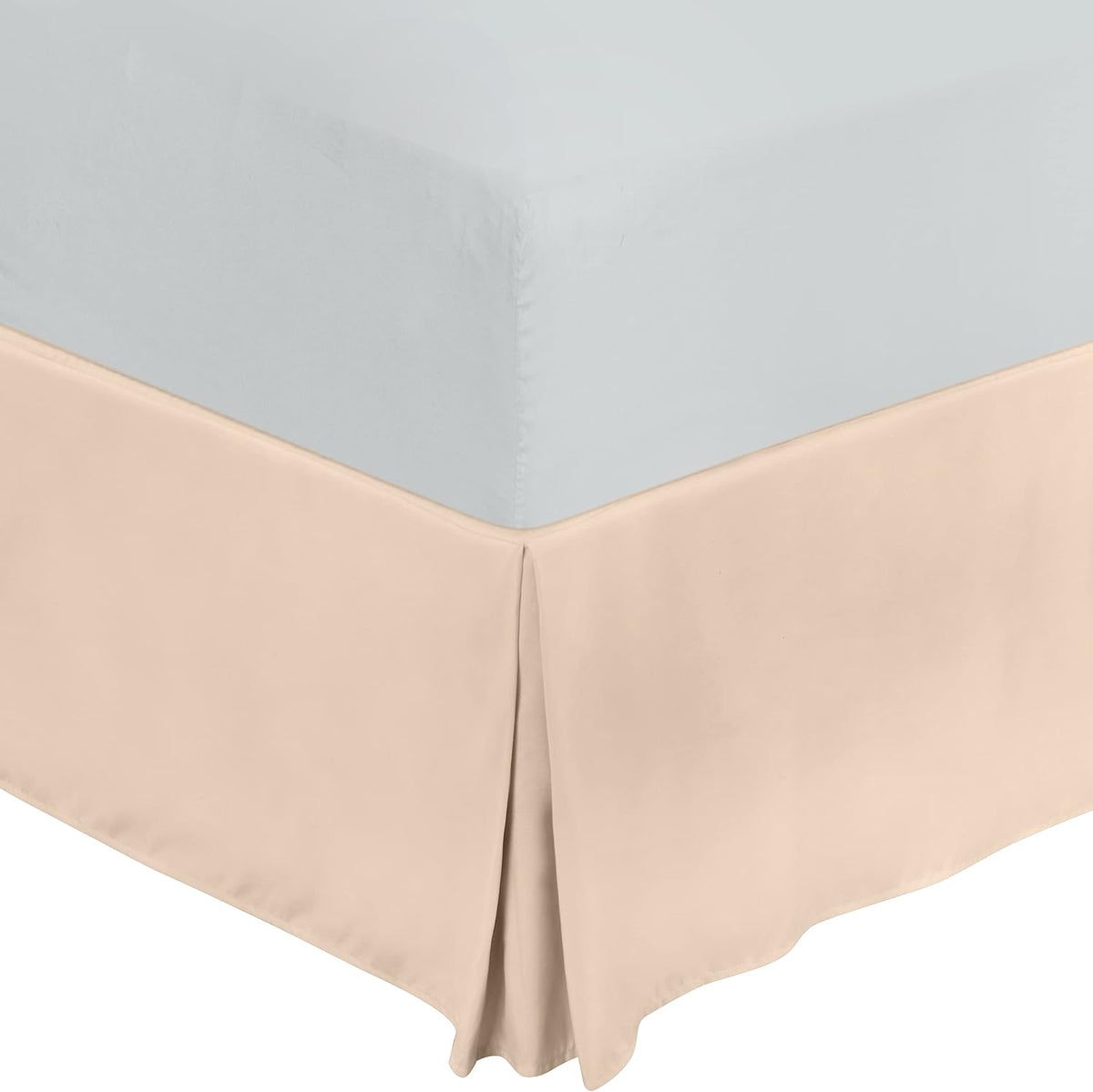 Top-down view of a light beige pleated bed skirt meeting the mattress corner.