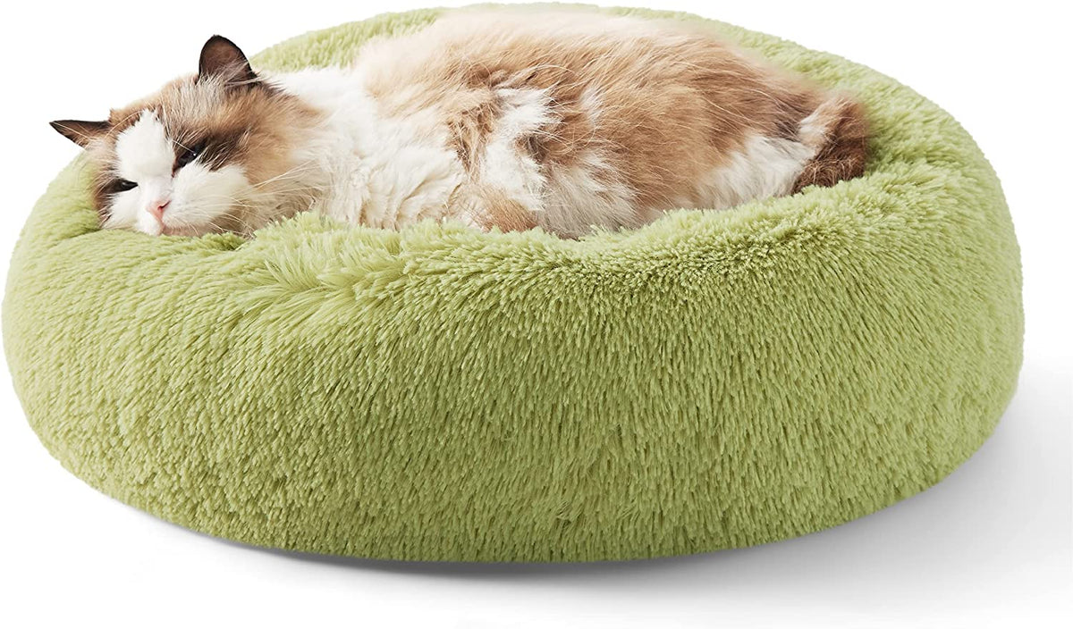 Green round faux fur donut bed with a longhaired cat curled up and resting
