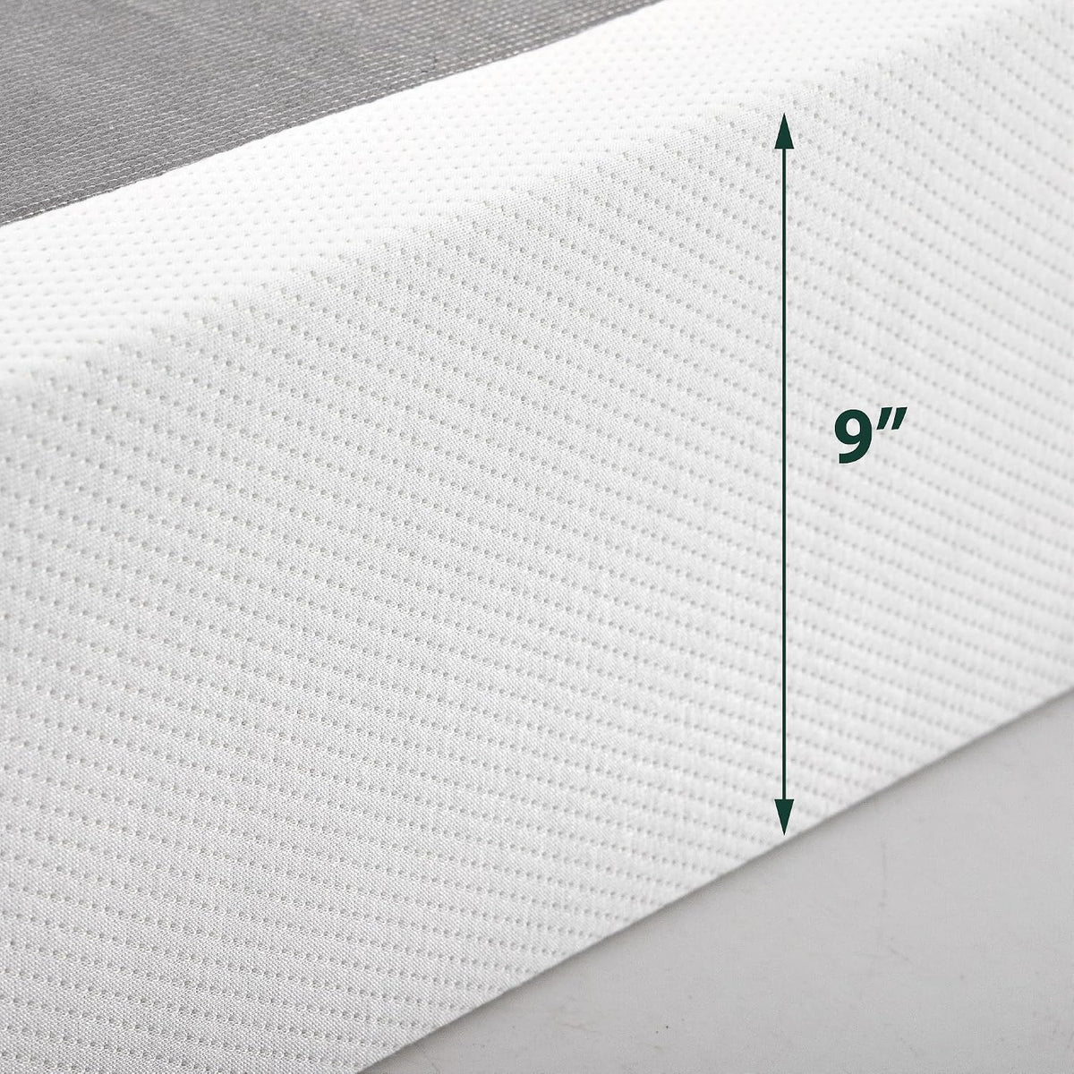 Close-up of white textured fabric on mattress edge with vertical measurement arrow