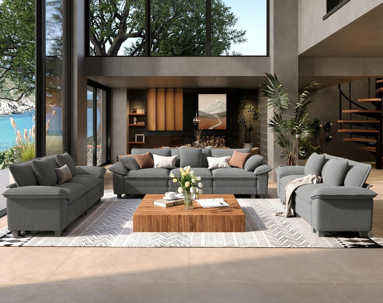 Gray three-seat sofa and matching loveseat in a modern two-story living room with plants and a spiral staircase