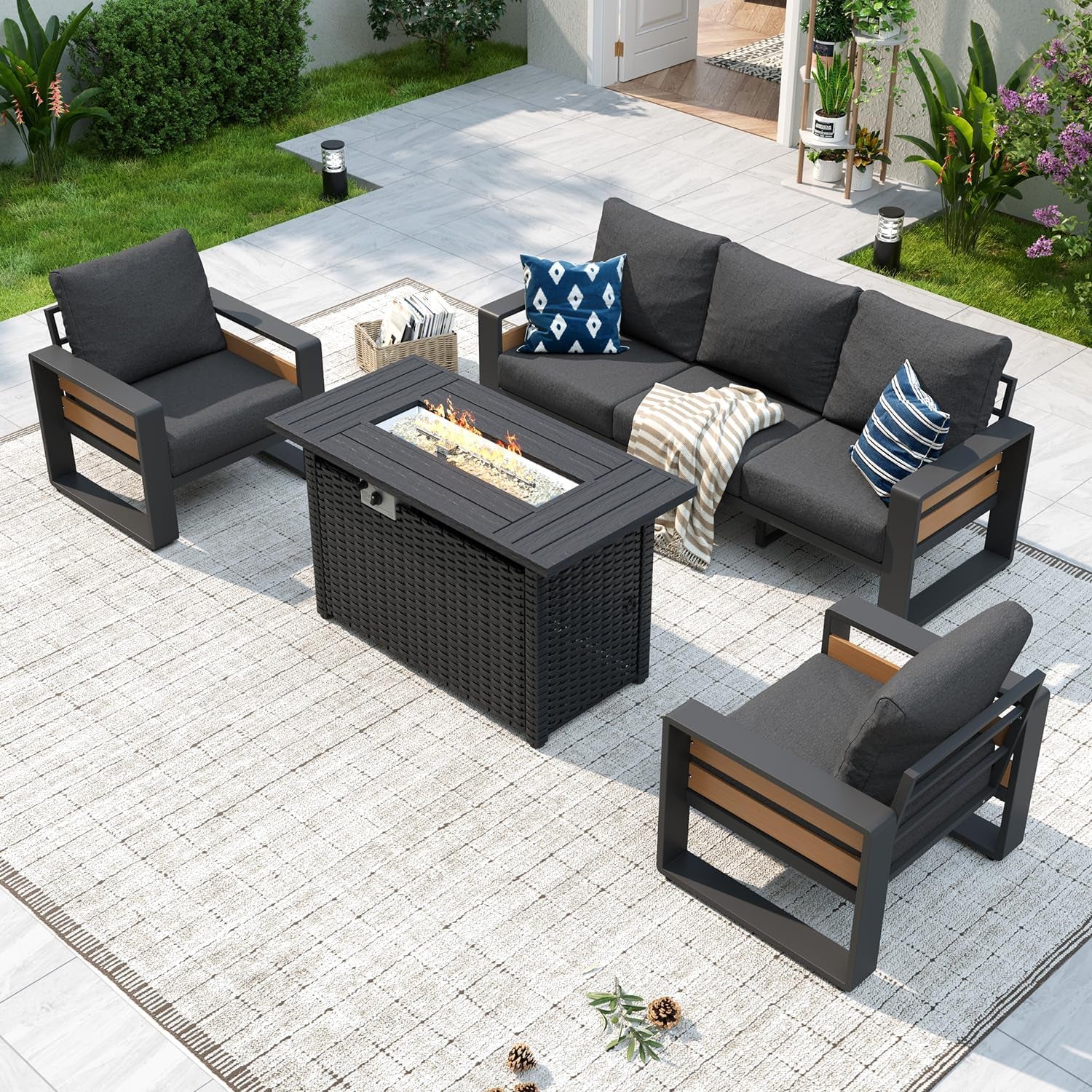 Aerial view of dark-gray cushioned outdoor seating grouped around a rectangular fire-pit table on a rug.