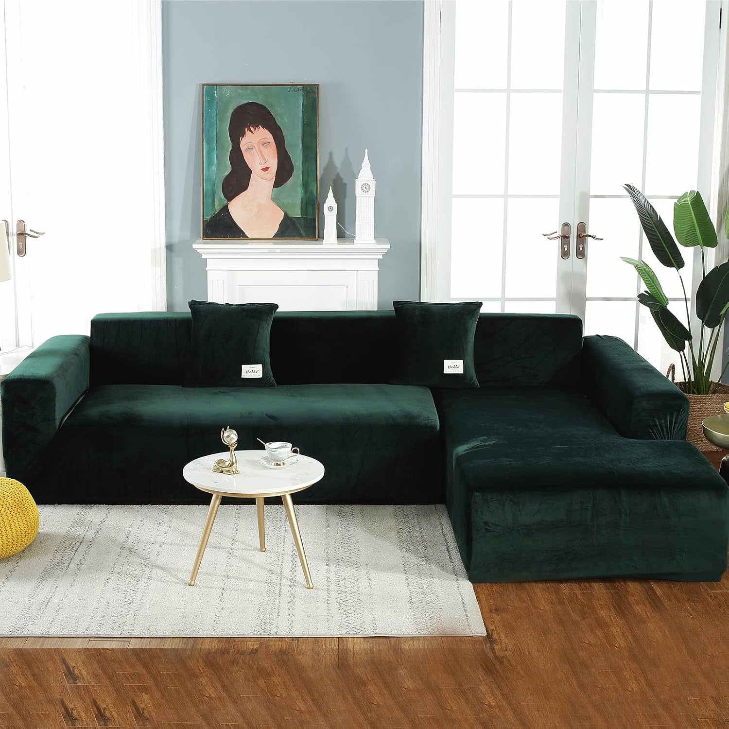 Dark green velvet L-shaped sectional slipcover styled in a living room with fireplace, coffee table and plants