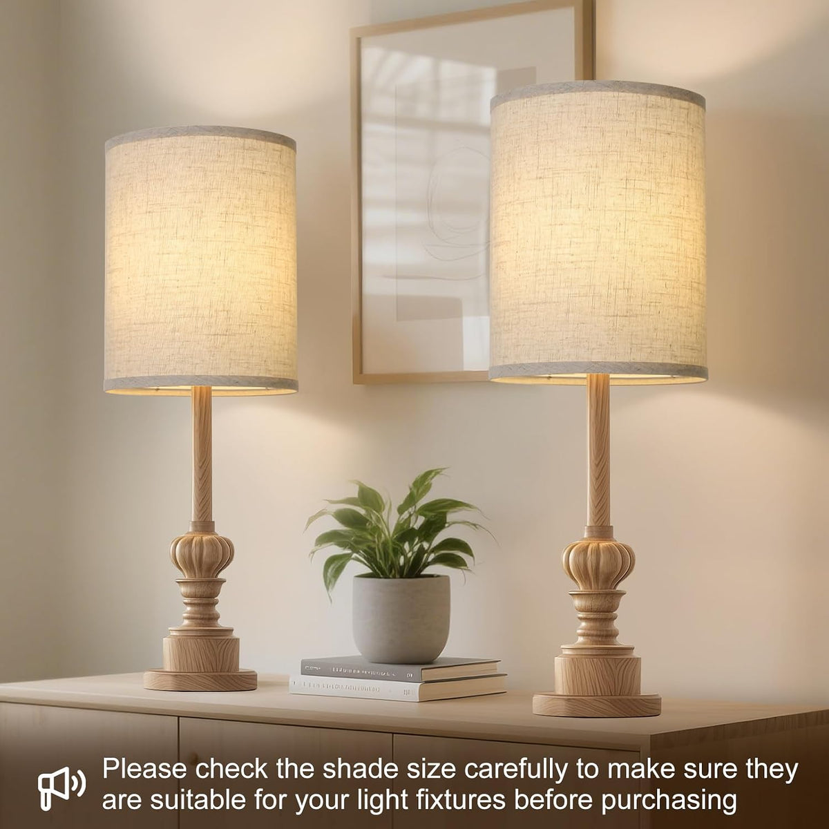 Pair of lit beige linen-look drum lampshades on wooden table lamps in a neutral living room