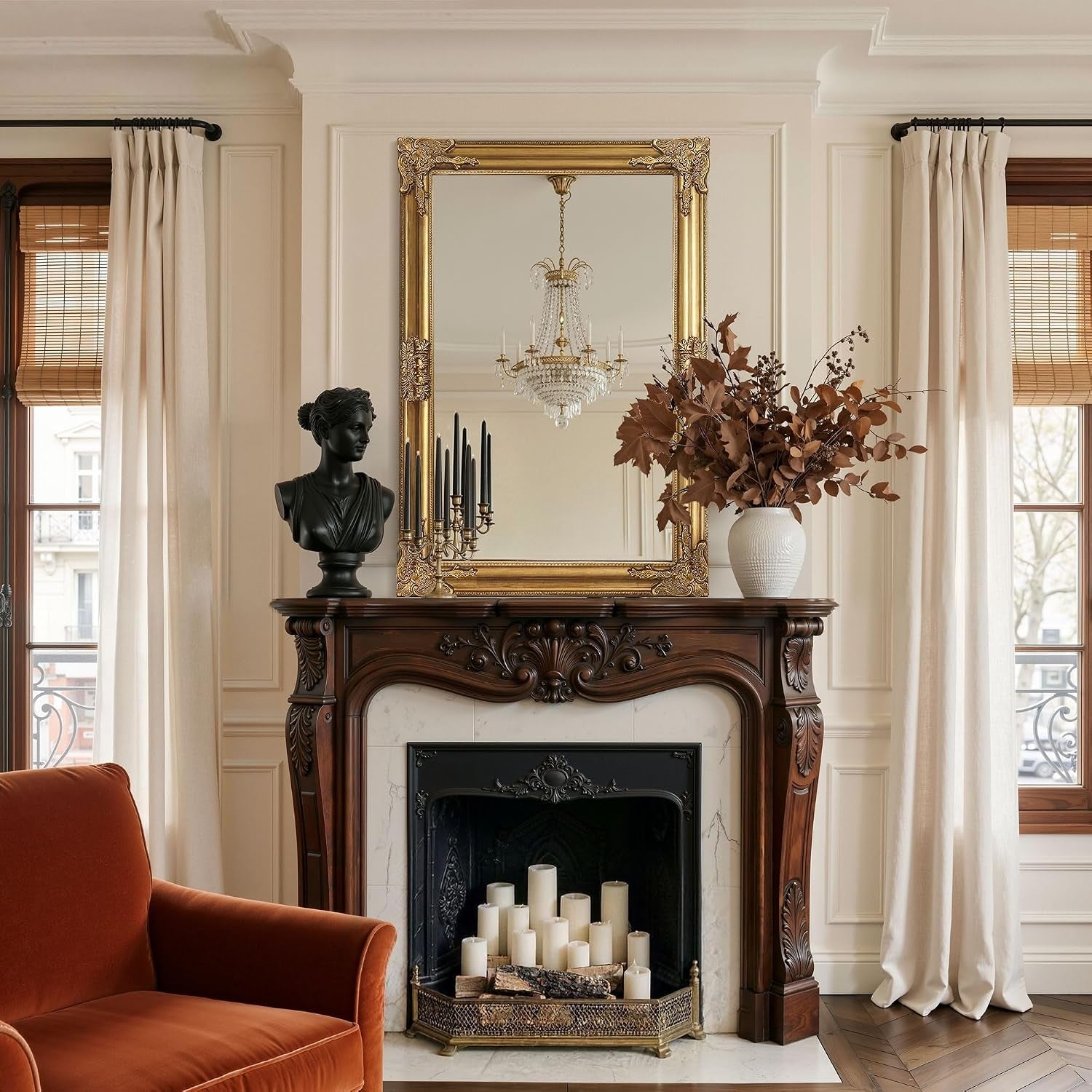 Gold baroque mirror hung above a dark wood mantel in a styled living room with vase and sculptural bust