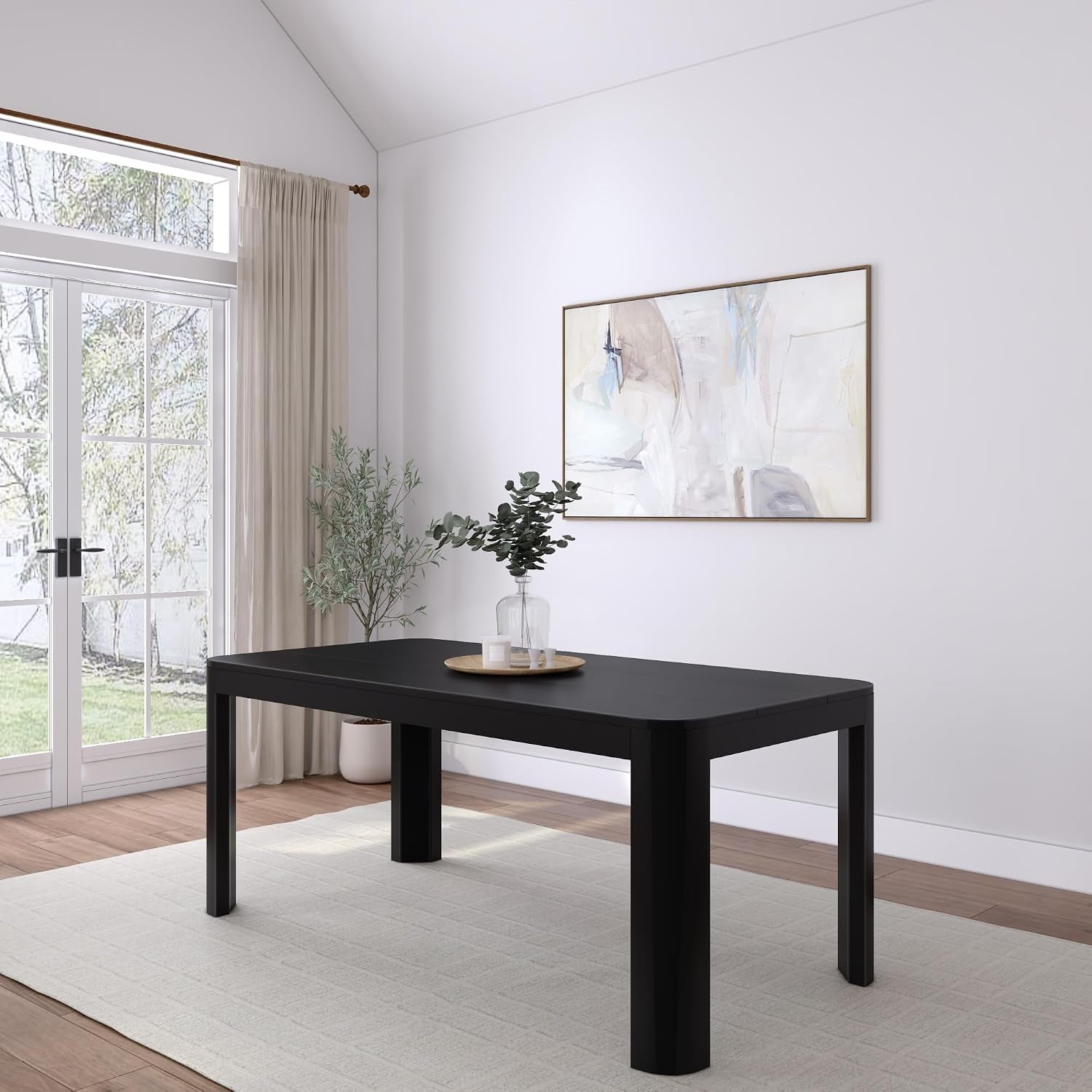 Rectangular dining table with rounded corners in a bright room, simple vase and tray on top, rug underneath