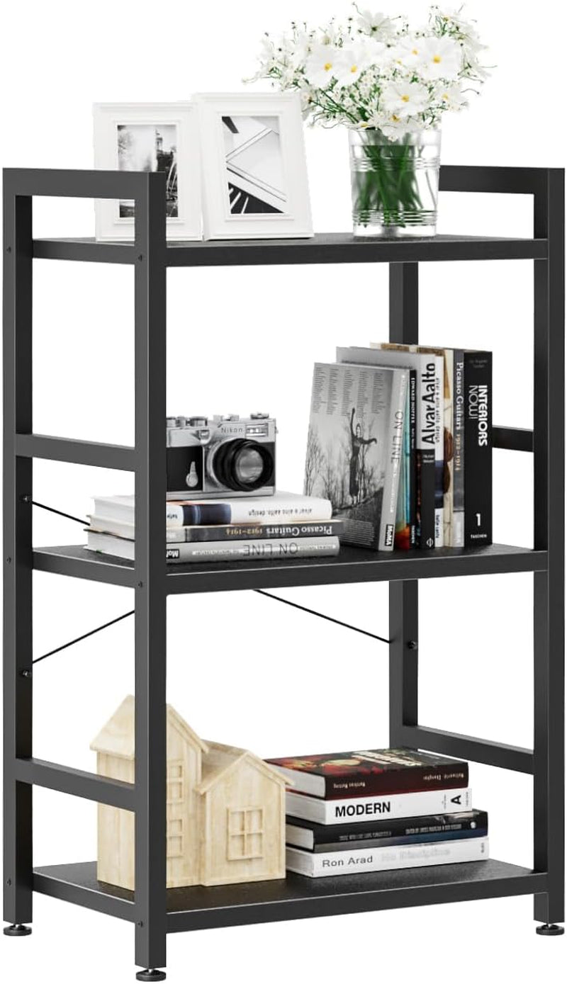 Three-tier black metal-frame shelf with books, camera, small house models and top vase of white flowers.