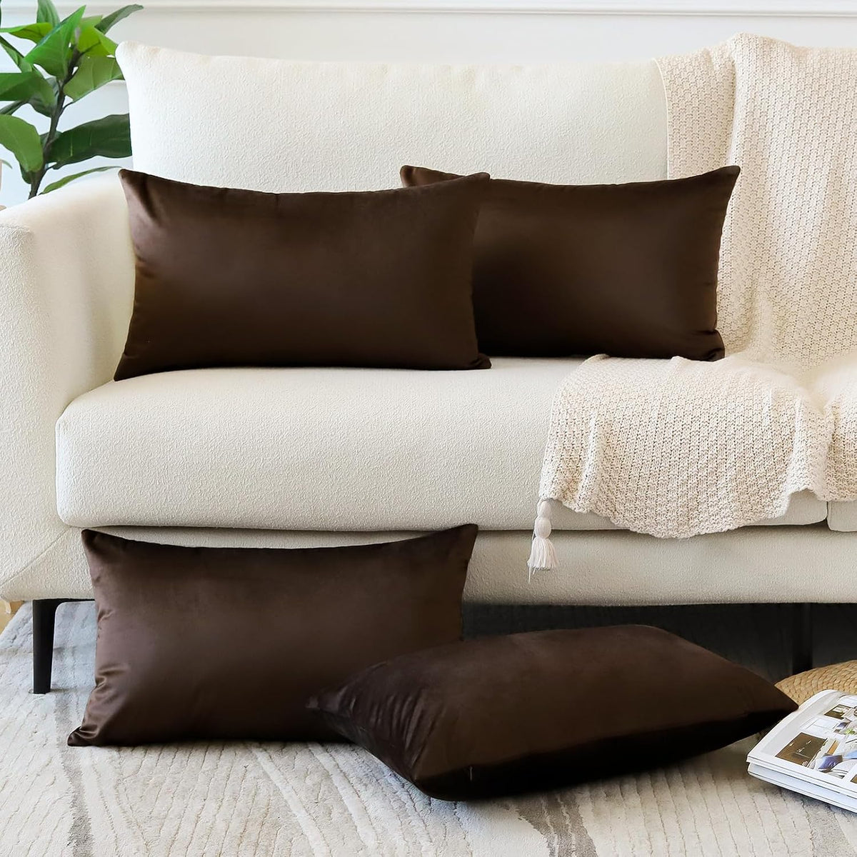 Two rectangular chocolate brown pillow covers on a cream sofa with brown pillows on the rug