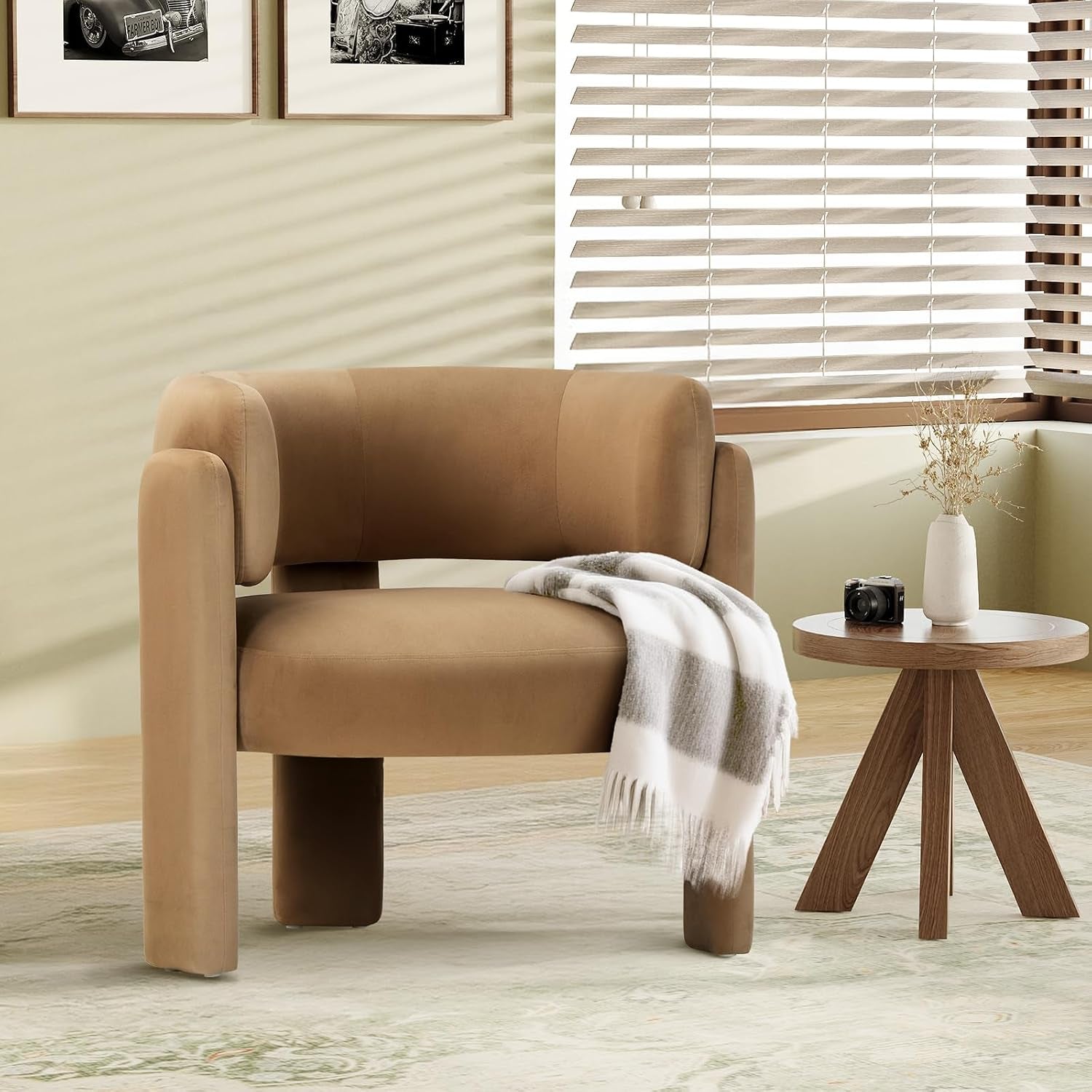 Tan barrel accent chair staged in a room beside a small round wooden table and window blinds