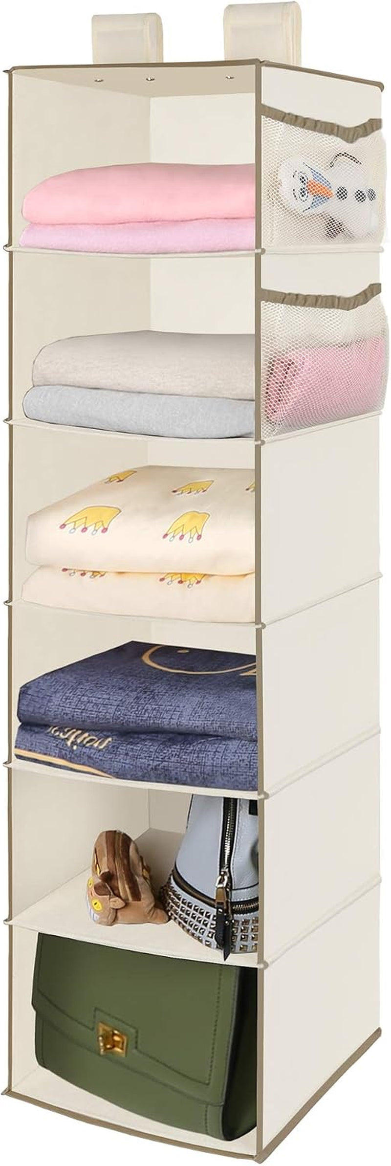 Cream-colored six-tier hanging closet organizer holding folded blankets, a purse and small toys.