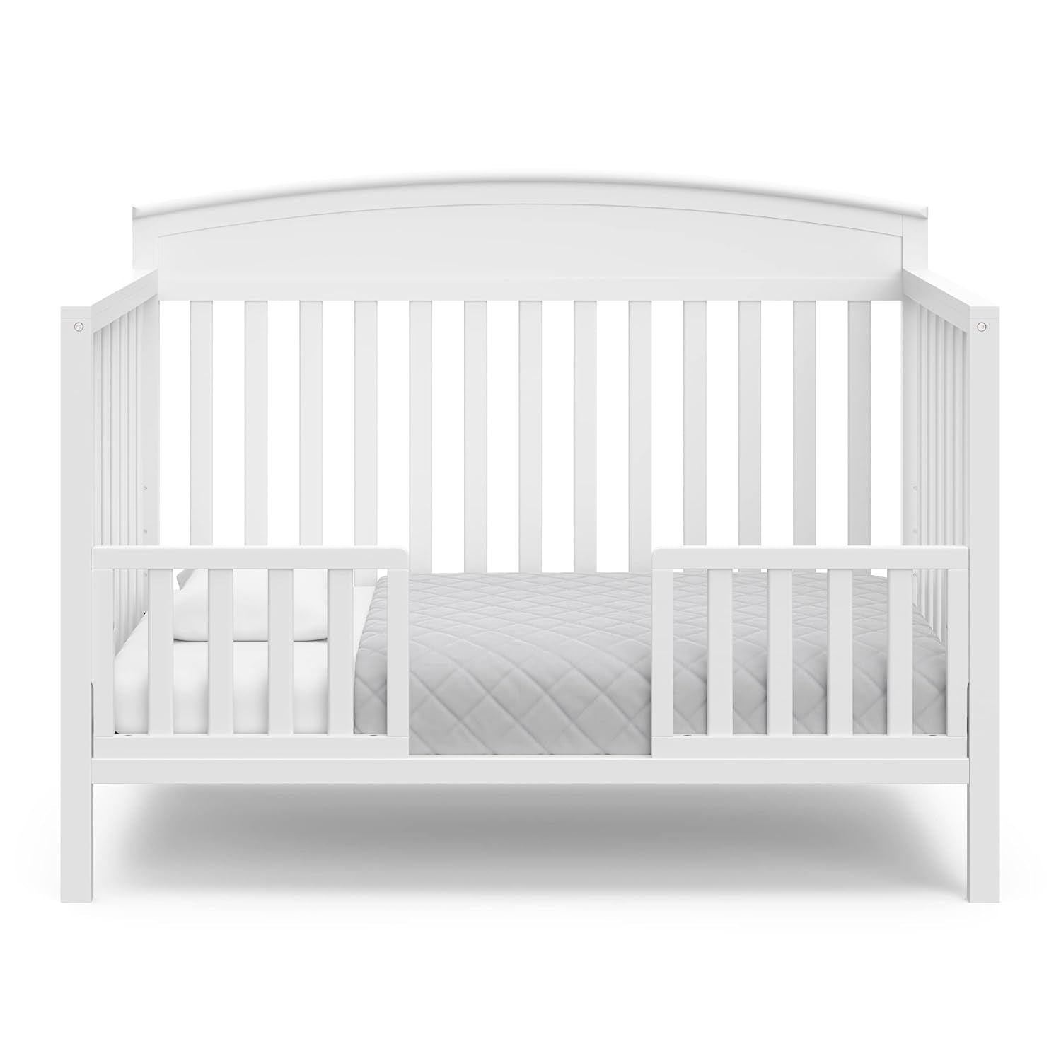 White convertible crib shown as a toddler/daybed with low mattress and safety rails at front