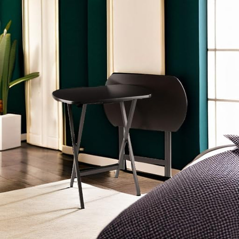 Single dark brown folding snack table set up in a bedroom scene against a green wall with folded table visible