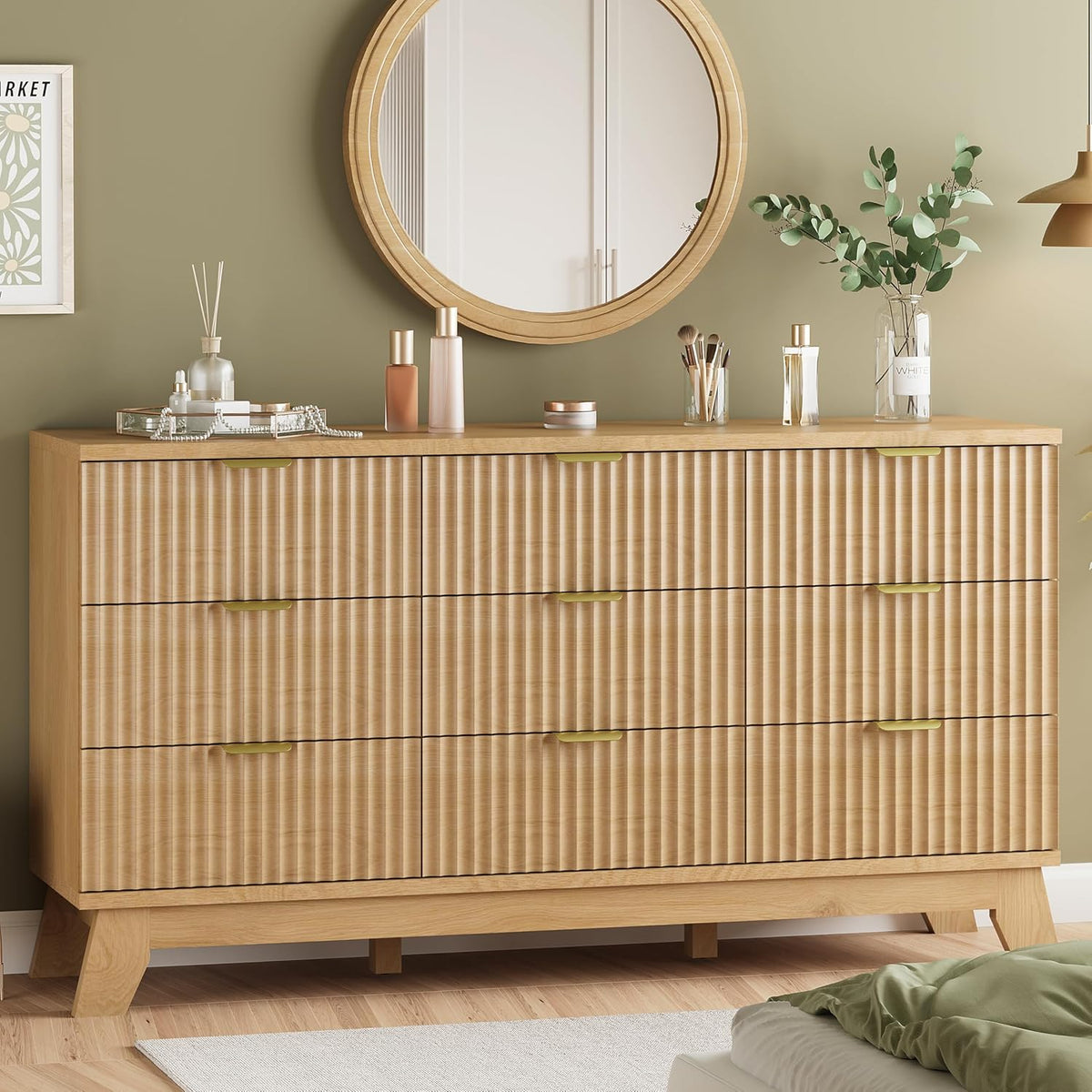 Top-front detail of a light oak wide dresser styled with small bottles, a vase and a round wood mirror.