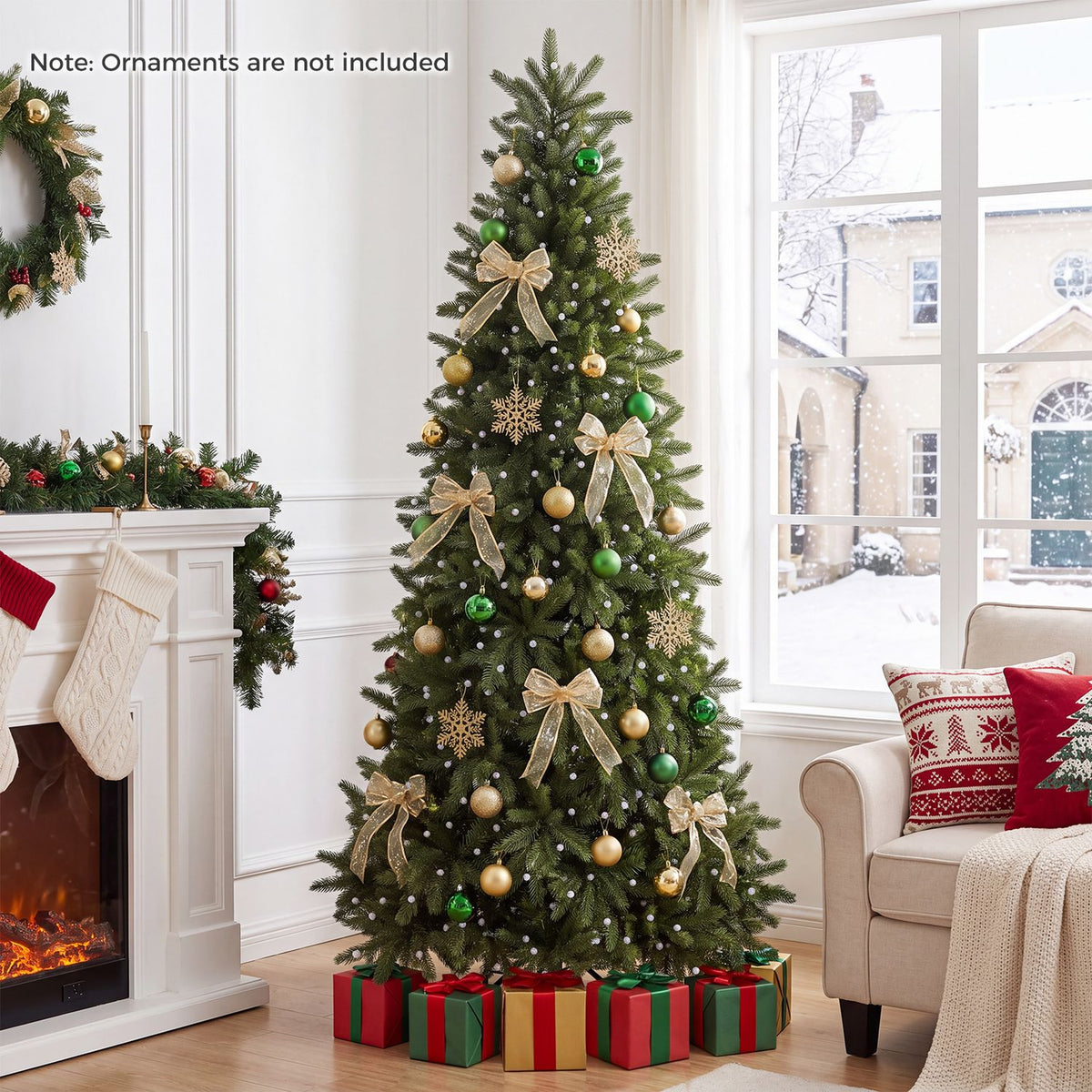 Green Christmas tree decorated with gold bows and ornaments beside a fireplace and window.