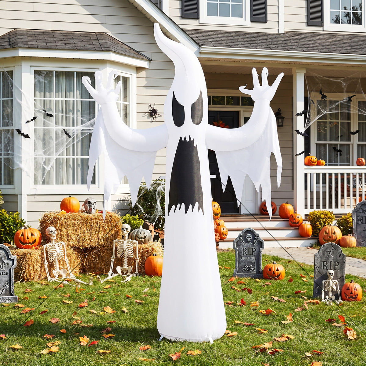 A tall white ghost inflatable stands on a lawn among pumpkins and Halloween decorations.